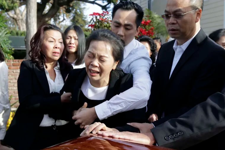Trung Do embraces his mother , Van Thanh Nguyen, as she weeps over the coffin of her daughter, Tin Nguyen, during the wake. Nguyen, 31, died in the mass shooting in San Bernardino, Calif. NICK UT / AP