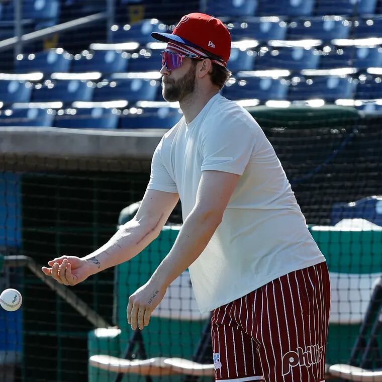 As Phillies Bryce Harper tosses a baseball during spring training, his scar from Tommy John elbow surgery is visible.