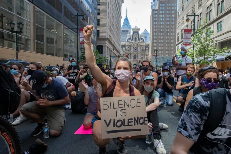 A protester raises a fist as others kneel in Philadelphia on June 4, 2020.