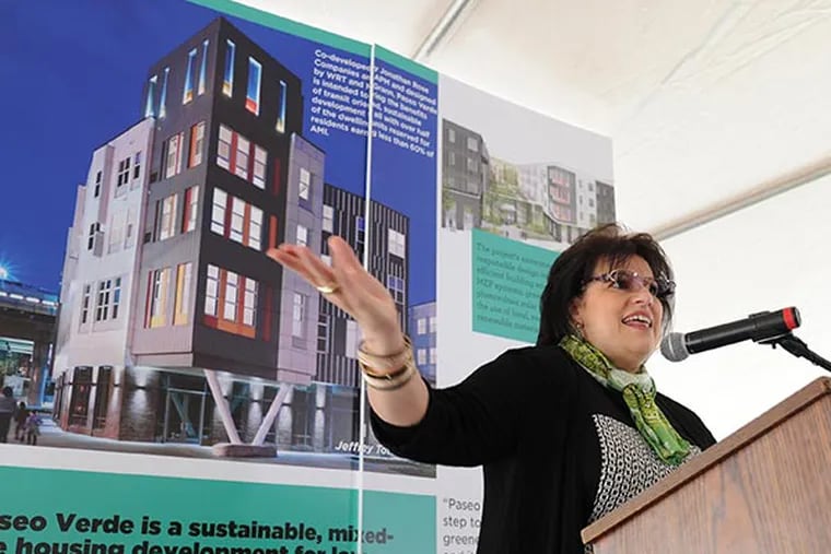 Nilda Ruiz, president of Asociación Puertorriqueños en Marcha, speaks at a ribbon-cutting ceremony for Paseo Verde, a complex of 120 affordable and market-rate apartments at Ninth and Berks Streets in North Philadelphia, Dec. 3, 2013.  The photo behind Ruiz shows the complex. (CLEM MURRAY / Staff Photographer)