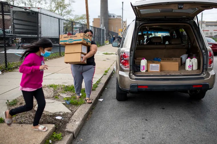 Milida Villanuvi, of North Philadelphia, carries food given away during the pandemic with the help of her daughter, Dayana Gonzales, 8, at Mary McLeod Bethune Elementary School on Thursday, April 30, 2020.
