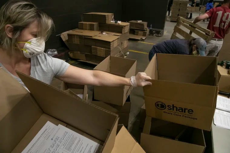 Volunteers grab absentee ballot applications to stuff into food boxes distributed by the city, school district, and nonprofit groups in Philadelphia last week.