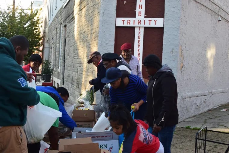 Residents choose from the produce dropped off by North Philadelphia residents Michael Jarman and Wiley Cunningham at 17th and Francis streets on Nov. 3. Cunningham started the food distribution when he moved to Francisville in the early 2000s.