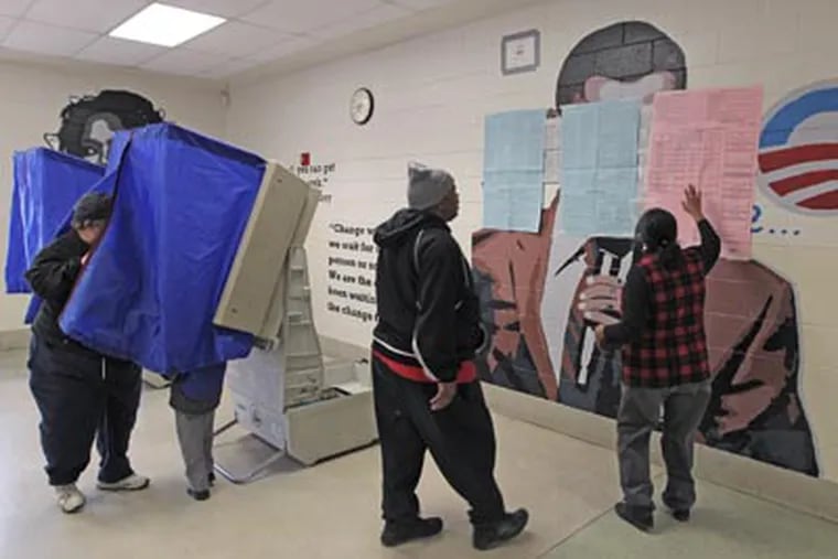 A poll worker, right, goes over a sample ballot with a voter, that is plastered over a mural of President Barack Obama in the voting area of polling place # 3518 at Benjamin Franklin Elementary School. A mural of President Barack Obama had to be covered in the school cafeteria after Republicans got a judge to issue an order that it must be covered so voters could not see the President's image as they waited to vote. (Michael Bryant/Staff)