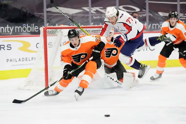 Flyers defenseman Justin Braun goes after the puck past leaping Washington Capitals right winger T.J. Oshie in the second period Thursday.