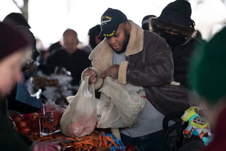 Vladymir Valentin of the U.S. Attorney's office receives food from Philabundance and other agencies beneath I-95 at Tasker and Front Ave. in Philadelphia on Wednesday. For the first time in its history, Philabundance is enacting its disaster plan in the city to distribute food to federal workers facing hunger because of the partial government shutdown. JOSE F. MORENO / Staff Photographer