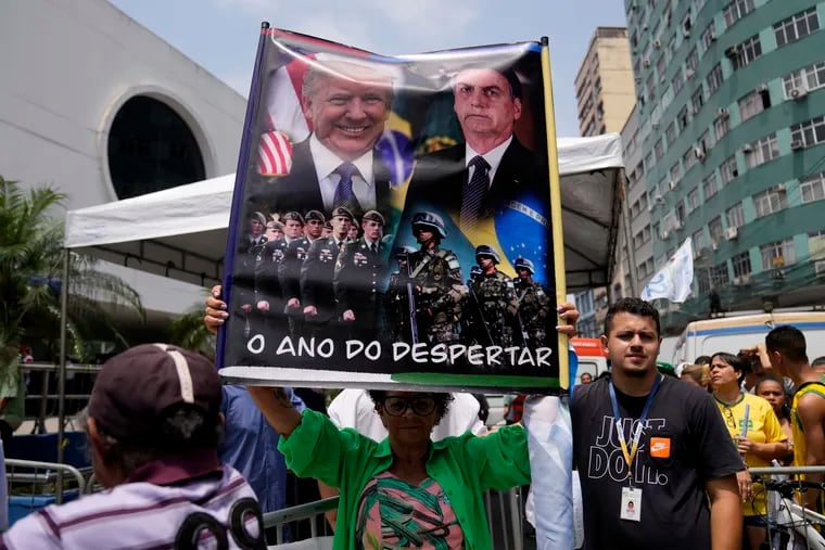 A supporter of Brazilian President Jair Bolsonaro holds a poster showing Bolsonaro and former U.S. President Donald Trump that reads, in Portuguese, "The year of the awakening," during a rally in Duque de Caxias, Brazil, last month.