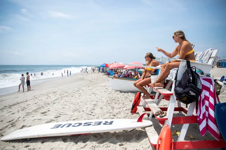 Lifeguards Megan O’Malley, 22, of Martin, N.J., (right), and Sara Jackson, 19, of West Chester, Pa., (left), keep watch as people enjoy the shore and hot weather in Cape May, N.J., on Thursday, July 21, 2022.