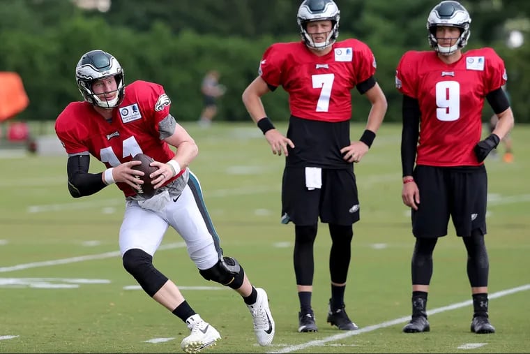 Eagles' Carson Wentz, left, scrambles as Nate Sudfeld, center, and Nick Foles, right, watch during Eagles Training Camp at the NovaCare Complex in Philadelphia, PA on August 1, 2018. DAVID MAIALETTI / Staff Photographer