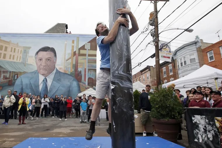 William Harvey attempts to climb the greased pole at the South 9th Street Italian Market Festival on Saturday, May 21, 2016. Harvey is traveling the nation experiencing local cultural community events.