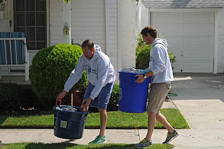 Justin Soulen and Bryan Leopold start a seasonal business in Margate named Convenient Collectors -- taking people's trash cans to-and-from the curb.  Here they deposit recyclables on the curb on N. Decatur Ave.  They plan to expand to other shore towns next year.  ( CLEM MURRAY / Staff Photographer )