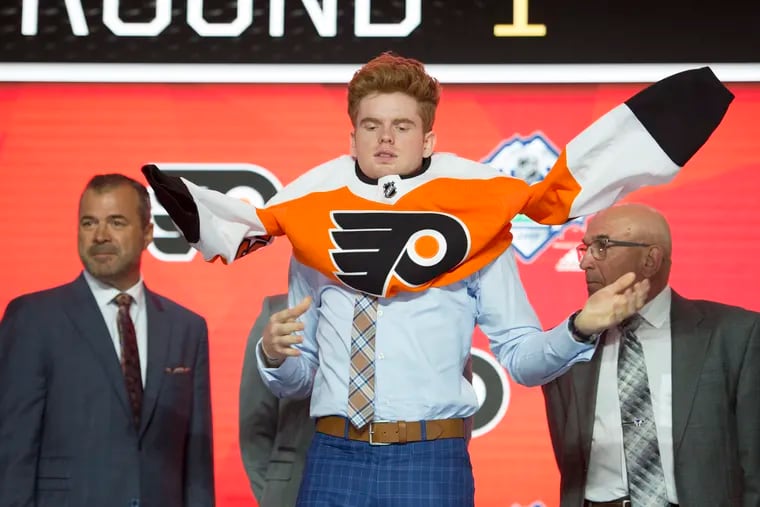 Cameron York puts on a Philadelphia Flyers jersey during the first round of the NHL hockey draft Friday, June 21, 2019, in Vancouver, British Columbia. (Jonathan Hayward/The Canadian Press via AP)