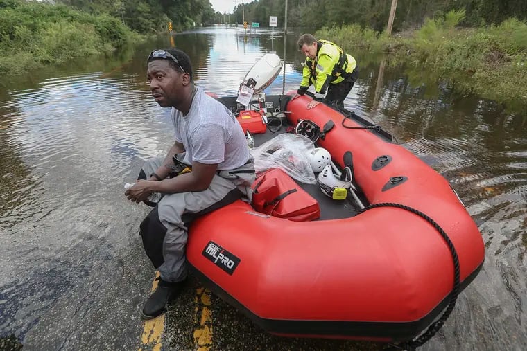 (Corrected caption) Pennsylvania Task Force 1 Urban Search & Rescue's Nkosi Wood (left) and Eric Geiger both Philadelphia Fire Rescue firefighters take a quick brake after a search on the Little Pee Dee river at the Harllees Bridge road in Dillon county, Tuesday, September 18, 2018. STEVEN M. FALK / Staff Photographer