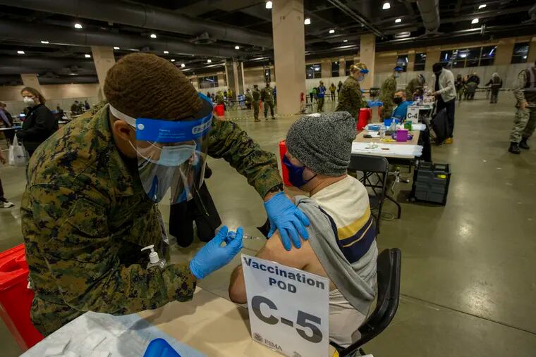 A man is vaccinated by military personnel at the Pennsylvania Convention Center.