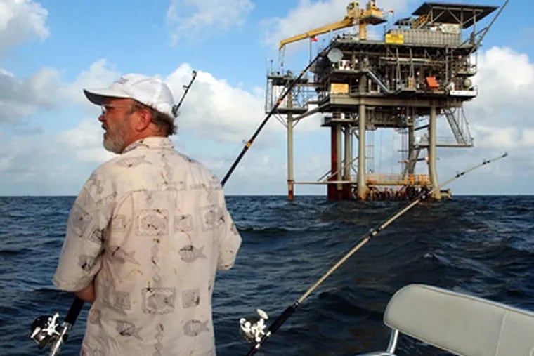 Angler Andy Hails of Montgomery, Ala., checks the fishing lines on his boat as he trolls the Gulf of Mexico near a natural gas well off the Alabama coast in this 2003 file photo. (AP Photo / Dave Martin, File)