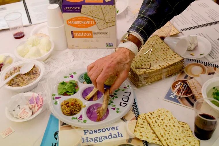Jester Heller picks up an symbolic item from the Seder plate during Passover dinner at the KleinLife Center in Elkins Park, Pa on April 17, 2019. BASTIAAN SLABBERS / For the Inquirer