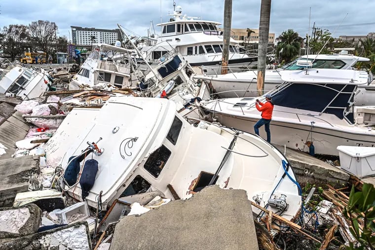 A man takes photos of boats damaged by Hurricane Ian in Fort Myers, Florida, on Thursday.