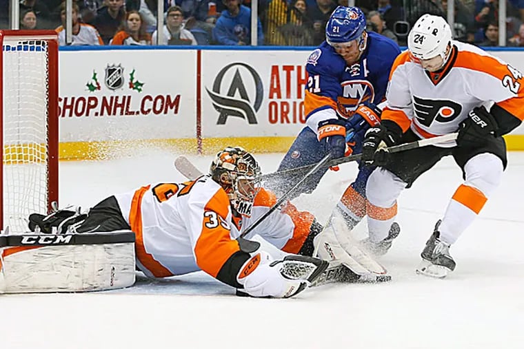 Islanders right wing Kyle Okposo and Flyers right wing Matt Read battle for control of the puck in front of goalie Steve Mason in the second period. (Kathy Willens/AP)