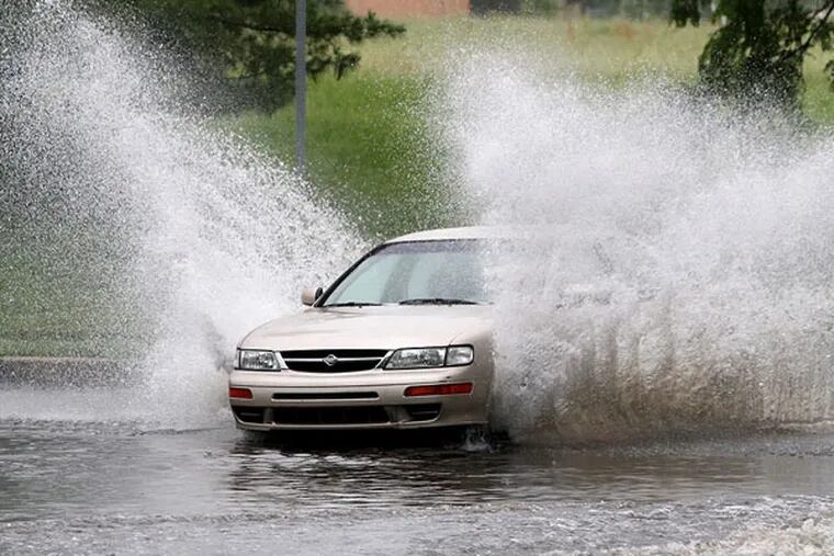 Virginia Drive in Fort Washington has long been prone to flooding. The street was flooded in several locations on Friday, but that did not stop this person in a Nissan sedan. (CHARLES FOX / Staff Photographer)