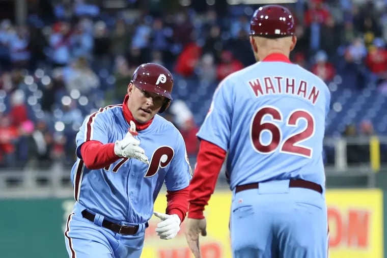 Phillies third-base coach Dusty Wathan, right, greets Rhys Hoskins after the slugger homered in an April game at Citizens Bank Park.