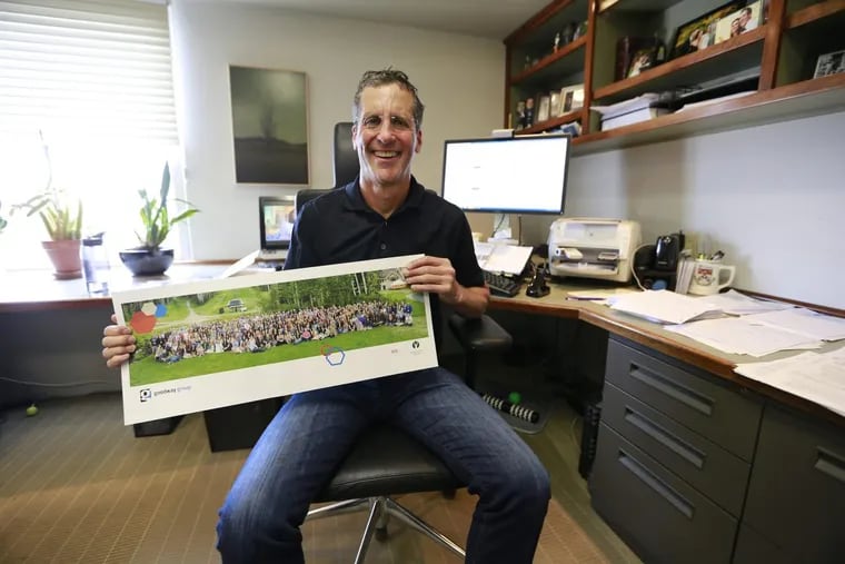 David Wolk, chief executive of Goodway Group in Jenkintown,  holds a photo of more than 300 of his employees.