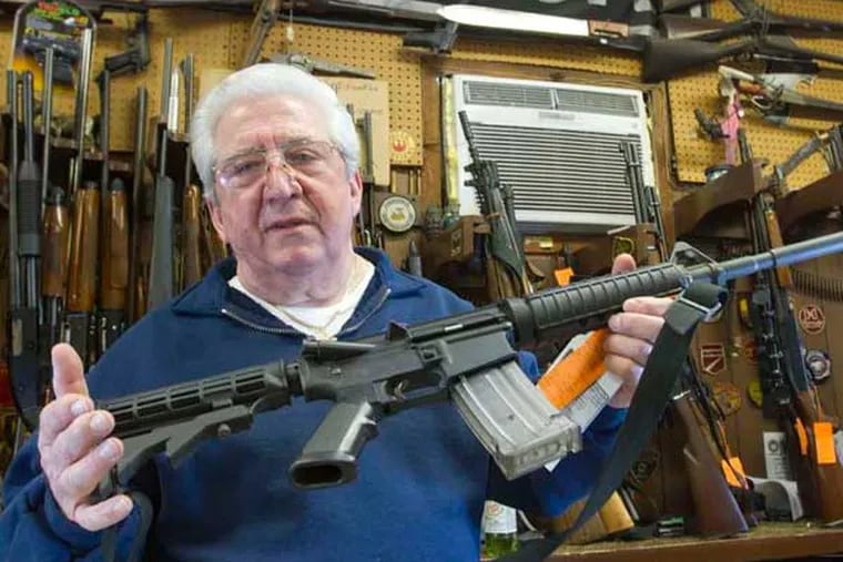 At Delia's Gun Shop on Torresdale Avenue, Fred Delia shows a Bushmaster AR-15 - the sort of weapon under scrutiny in Delaware and elsewhere. (David M Warren / Staff)