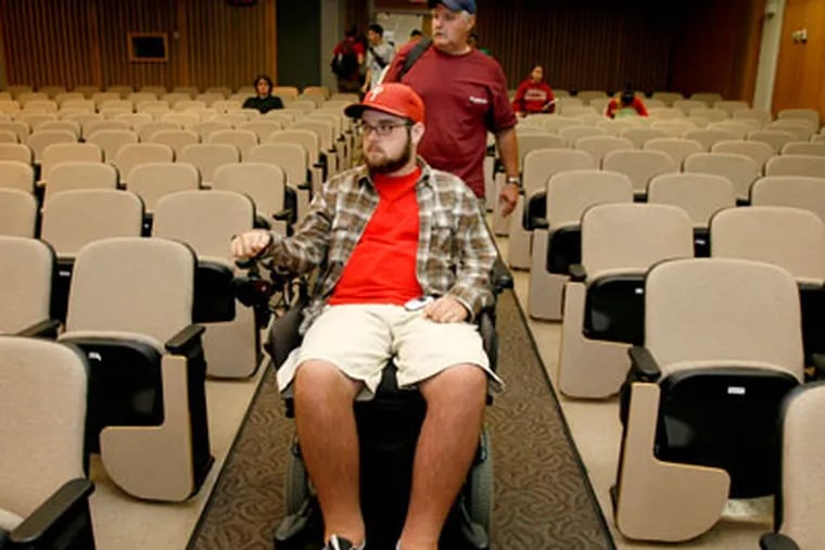 Rob Wunder III makes his way into a lecture hall at Temple University with the help of his father, Rob Wunder, Jr. Rob, Jr. retired from his job as a school teacher to help his son, a quadraplegic, go through college. (Charles Fox / Staff Photographer )