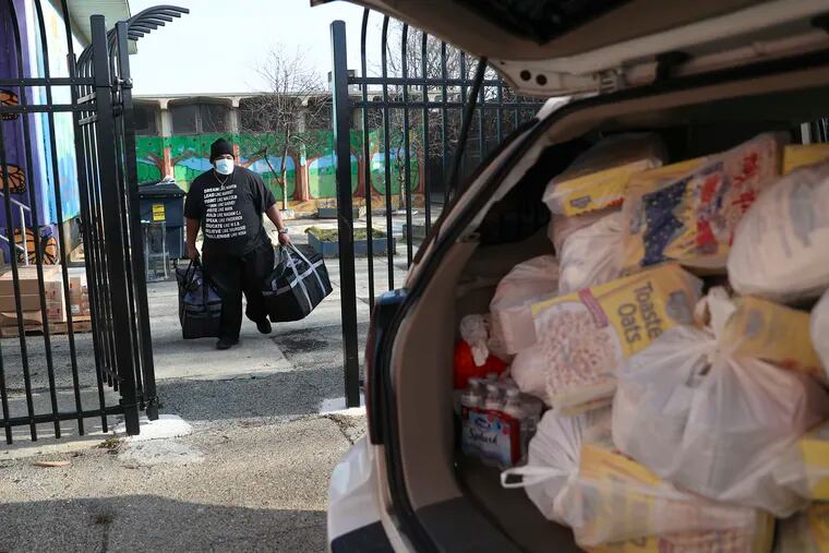 Michael Mitchell carries bags of food to his vehicle at S. Weir Mitchell Elementary in Southwest Philadelphia on Wednesday, Jan. 13, 2021. Families are relying increasingly on school meals and experiencing more food insecurity due to the pandemic.