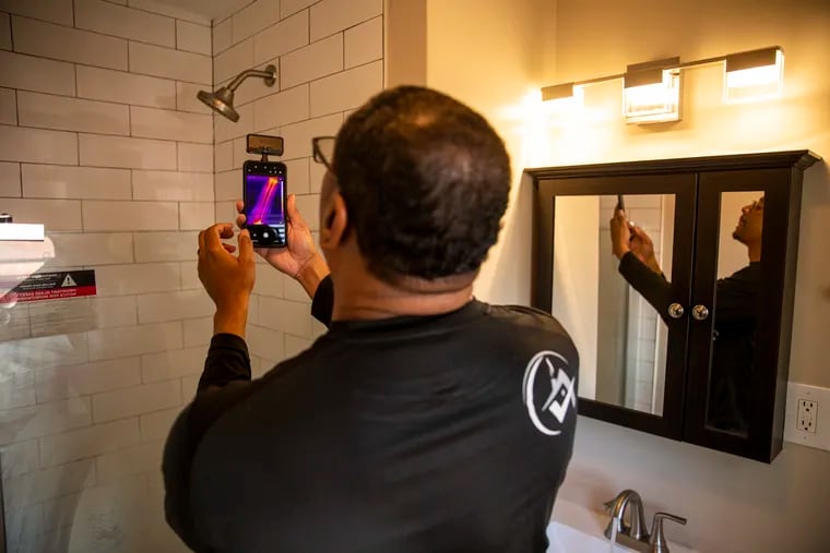 Ben Poles, owner of Rest Assured Inspections, takes a photo and checks the temperature of the water in the shower during a home inspection in Drexel Hill.