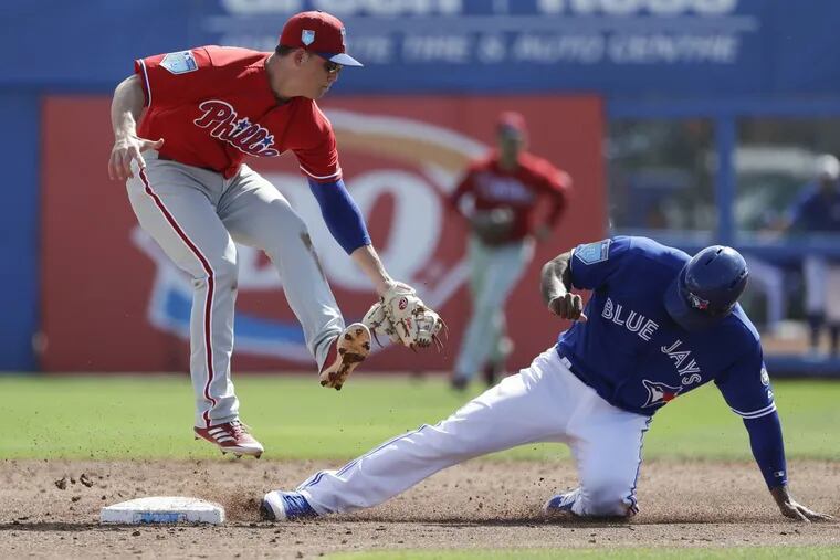 Scott Kingery leaps as Toronto’s Teoscar Hernandez steals second base in a spring training game.