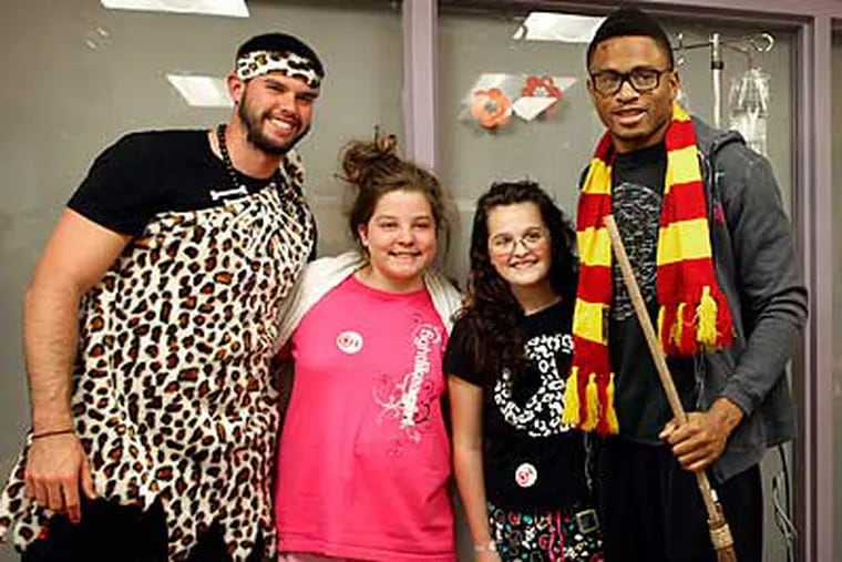 Chas Henry, left, and Nnamdi Asomugha pose with patients at Children's Hospital. (Laurence Kesterson/Staff Photographer)