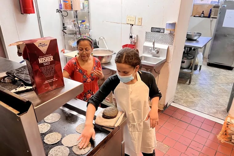 Masa Cooperativa member Carmen Guerrero (left), with Maria Roxana Amaya Lemus, making tortillas on the grill in the cooperative's kitchen at 1149 S. Ninth St. on March 19, 2023.