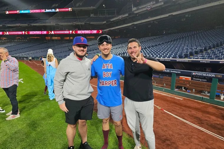 Carson Skelton (left), Phillies rookie Orion Kerkering, and Jared Pollock (right) celebrate the Phillies' NLDS-clinching win over the Atlanta Braves. Kerkering is wearing a shirt designed by Pollock.