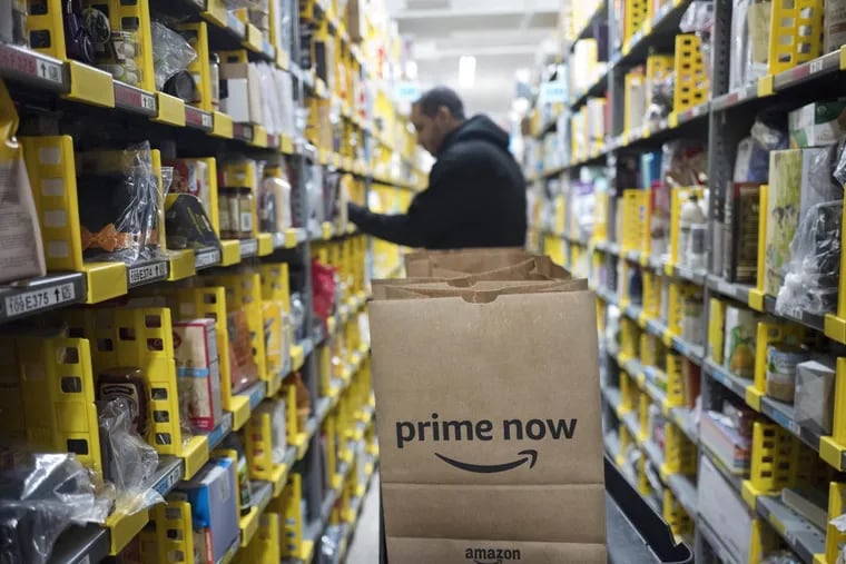 A clerk reaches to a shelf to pick an item for a customer order at the Amazon Prime warehouse in New York.