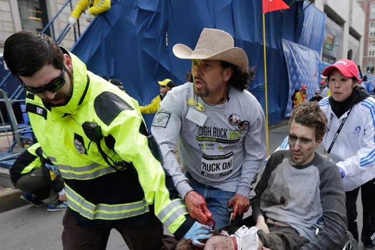 An emergency responder and volunteers, including Carlos Arredondo in the cowboy hat, push Jeff Bauman in a wheel chair after he was injured in an explosion near the finish line of the Boston Marathon Monday, April 15, 2013 in Boston. (AP Photo/Charles Krupa)