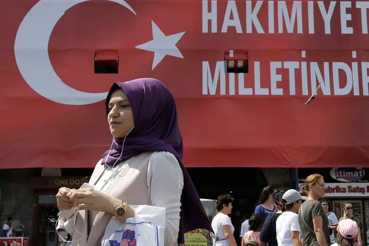 A Turkish woman passes under a banner that reads &quot;Sovereignty belongs to the people&quot; in Istanbul. The government has launched a sweeping crackdown since the failed coup last month.