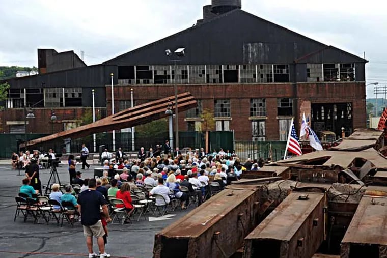 Coatesville Remembers, a ceremony held at The National Iron & Steel Heritage Museum honoring the 13th anniversary of 9/11, gets underway Sept. 11, 2014 with two tridents, or "trees" as they were termed when they were made at the old Lukens Steel plant back in the 1960s, flanking the participants.  ( CLEM MURRAY / Staff Photographer )