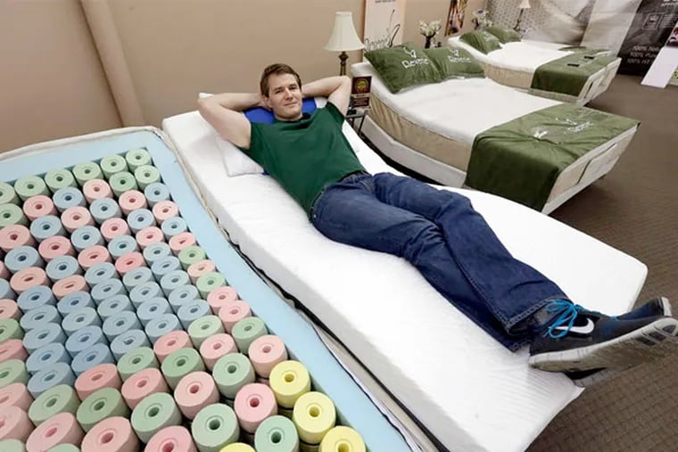 Martin Rawls-Meehan, CEO of Reverie, next to a cutaway example of on of his adjustable beds. (Duprey / AP)
