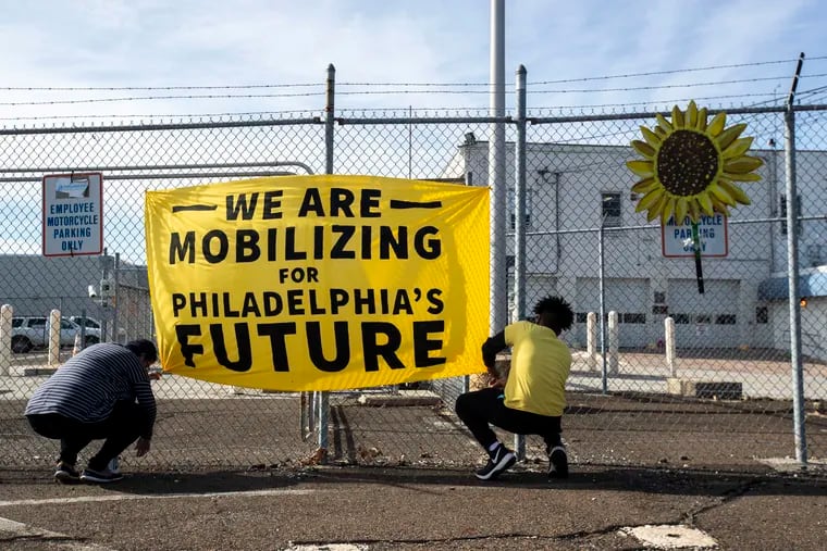 Becca Ersek, of North Wilmington and Cameron Powell, of University City, adjust a sign outside of the Philadelphia Energy Solutions oil-refinery complex last month. Philly Thrive organized a 10-hour occupation at the refinery.