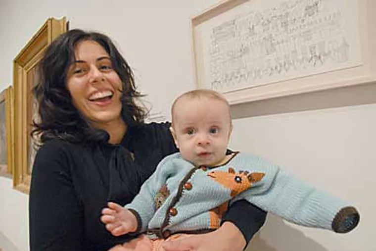 Artist Mia Rosenthal with son Kirby at the Pennsylvania Academy of the Fine Arts, next to her "Postpartum Portrait," an inventory of her closet. (APRIL SAUL / Staff Photographer)