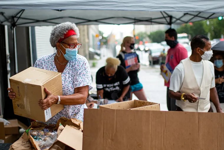 Carmen Lassus, a volunteer at The Center for Returning Citizens Community Healing Center, helps hand out food to people in the community along Broad Street in North Philadelphia in July.