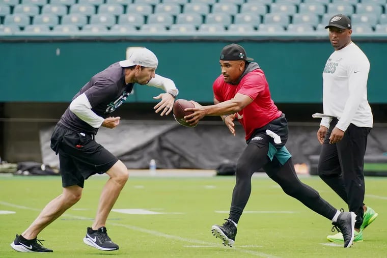 Eagles quarterback Jalen Hurts (right) runs a drill with offensive coordinator Shane Steichen as quarterbacks coach Brian Johnson looks on during practice at Lincoln Financial Field in South Philadelphia on Friday, June 4, 2021.
