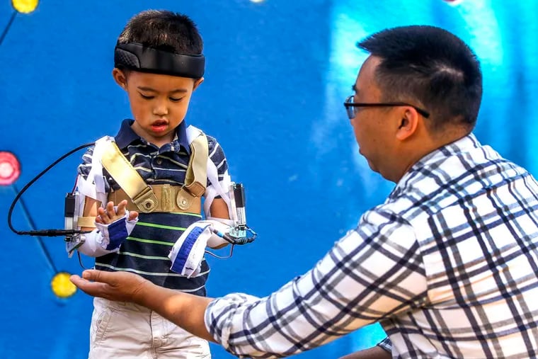 Five-year-old Max Ng, whose arms are paralyzed due to acute flaccid myelitis, is able to lift his hand and touch the hand of his father Ted Ng, thanks to a custom motorized orthotic brace that mechanical engineering undergraduate students at UC San Diego have created, during a demonstration of the brace at Rady Children's Hospital on Friday, June 14, 2019 in San Diego, Calif. (Hayne Palmour IV/San Diego Union-Tribune/TNS)