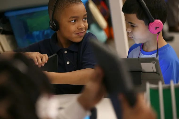 Lamar Eskridge, 7, left, and Nasir Warren, 7, use a reading program on iPads in their first-grade classroom at Alain Locke Elementary School in West Philadelphia.