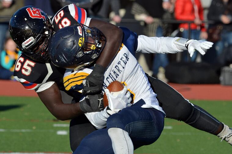 Germantown Academy lineman Elijah Wroten (65) wraps up Penn Charter running back Edward Saydee (6) in an Inter-Ac League game last November. Photo by Mark C Psoras