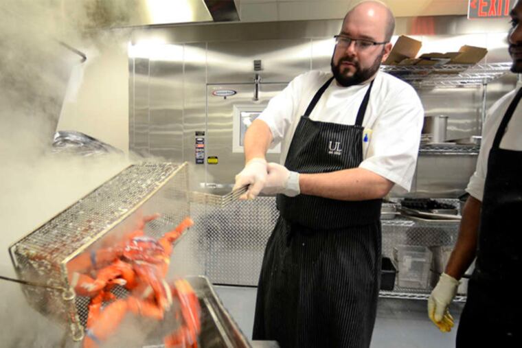 Banquet chef Matthew DiGiovanni (left) and Hailu Godoy work with lobsters in preparation for the Union League's champagne-filled New Year's Eve party.
