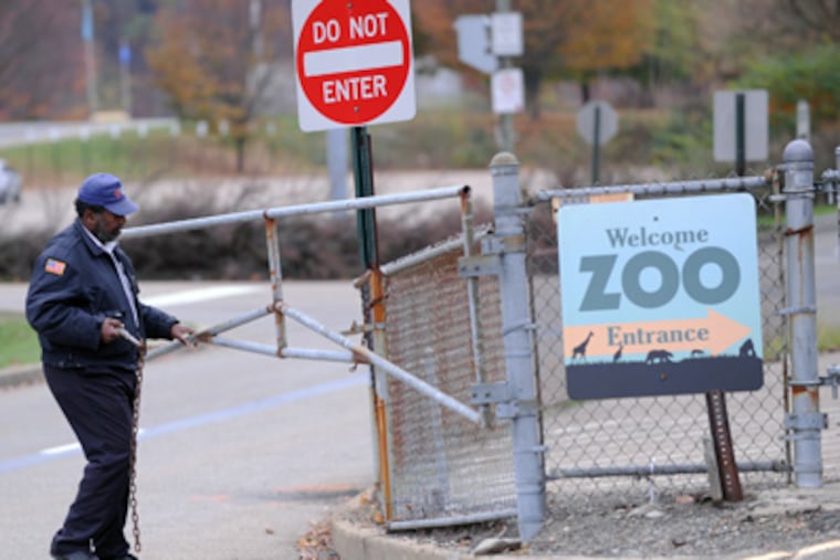 A security guard closes the gate at the Pittsburgh Zoo, where zoo officials say a young boy was killed after he fell into the exhibit that was home to a pack of African painted dogs, who pounced on the boy and mauled him, Sunday, Nov. 4, 2012. (AP Photo/John Heller)
