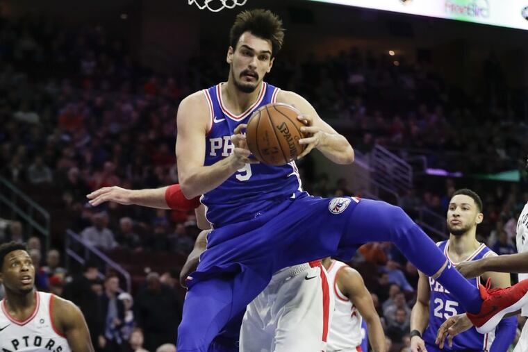 Sixers forward Dario Saric grabs a first-quarter rebound past Raptors center Jonas Valanciunas on Thursday, December 21, 2017 in Philadelphia.