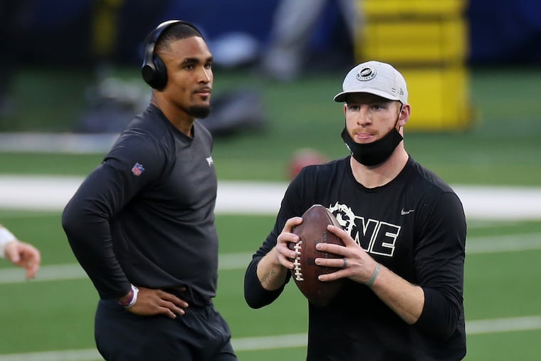 Eagles quarterbacks Jalen Hurts (left) and Carson Wentz warm up before a December 2020 game against the Dallas Cowboys.