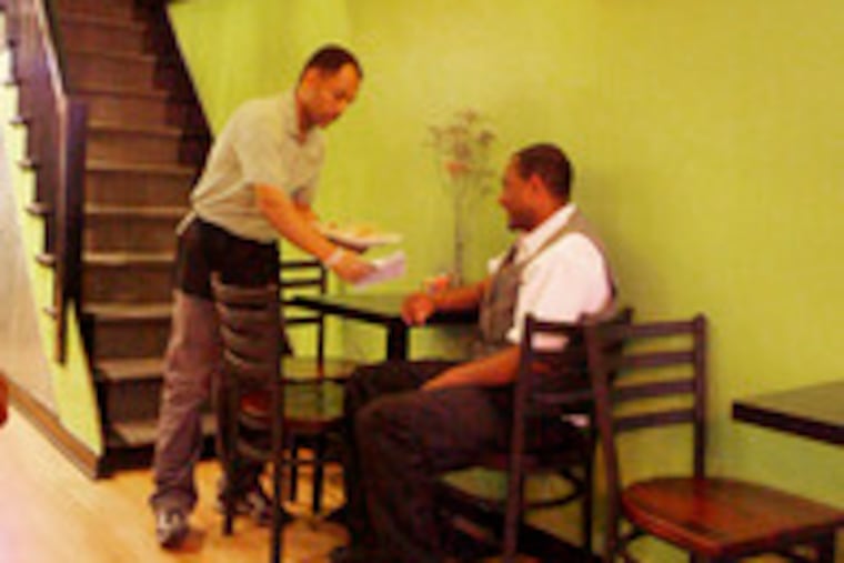 Owner Solomon Getnet serves customer Dileytoy Abera at Almaz Cafe. The cafe, at 140 S. 20th St., is a coffeehouse and a low-budget Ethiopian restaurant.